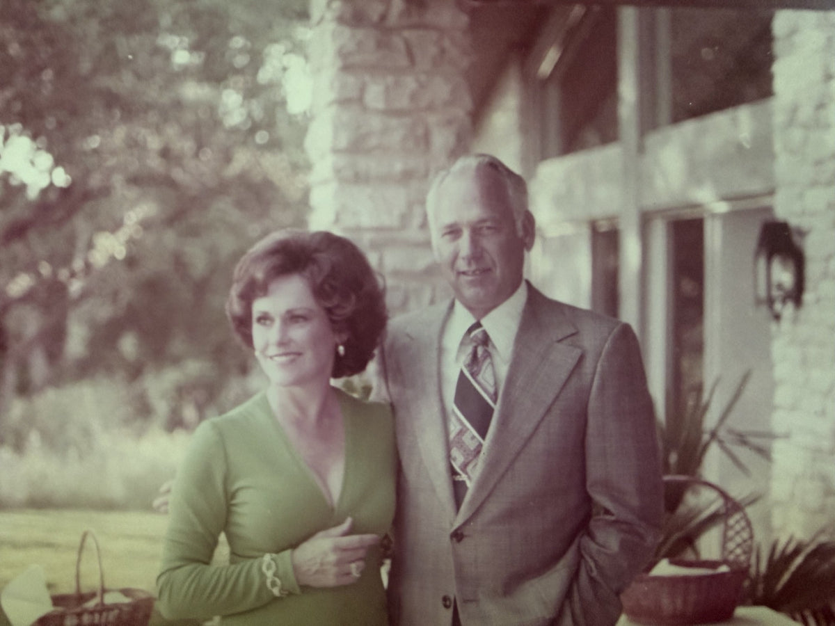 Archival photograph of Ringo in a suit and patterned tie beside Jean in a green dress, standing together on a stone porch in Rockport, TX.